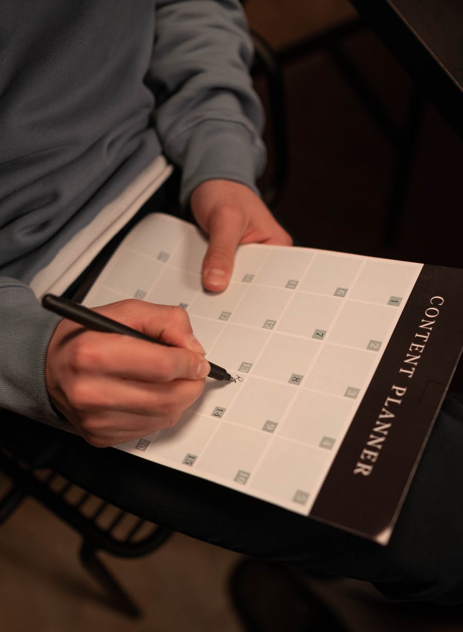 person writing on a calendar planner